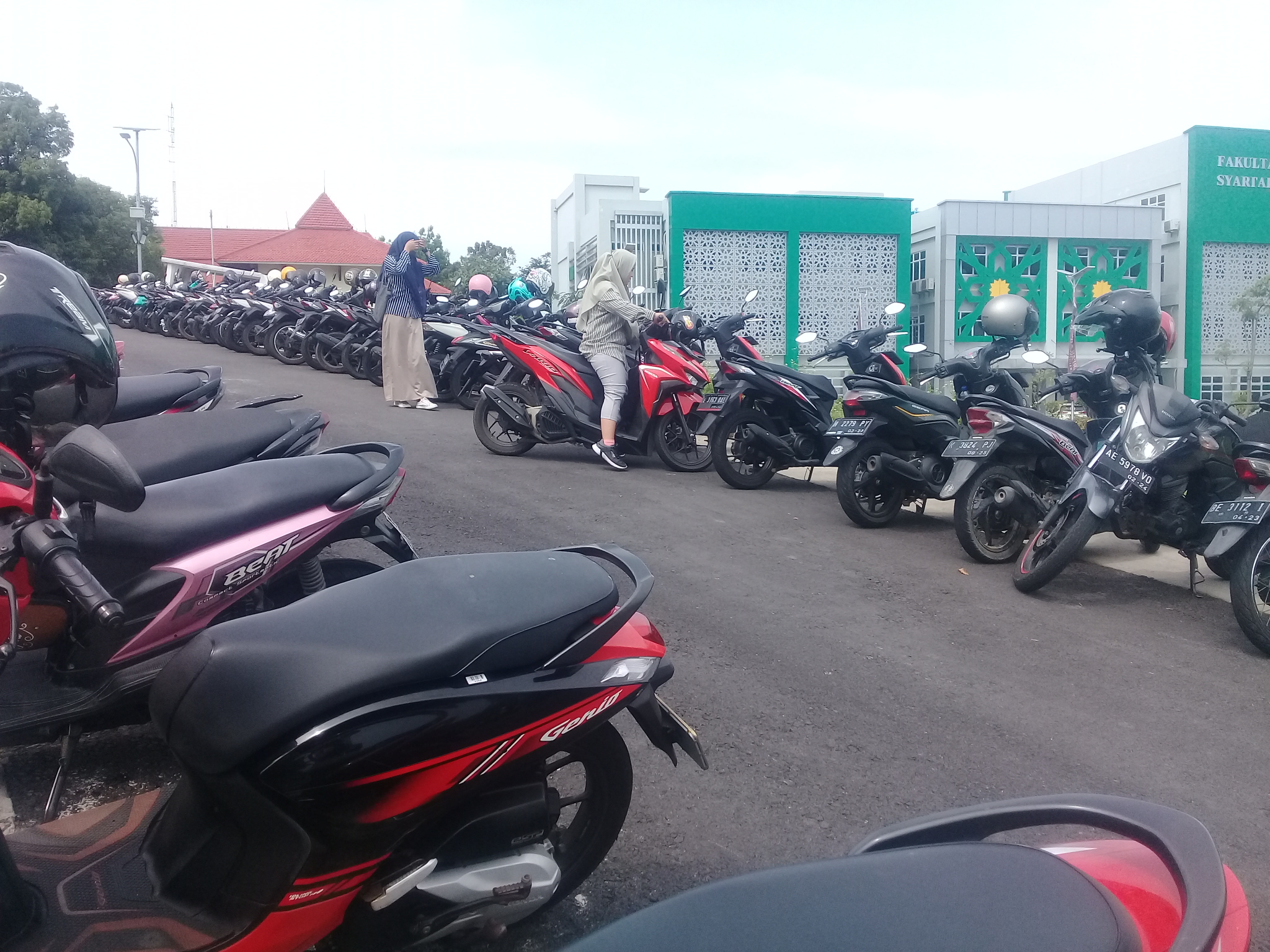 Dua mahasiswa yang sedang memarkir motor di belakang gedung L--sisi Utara bundaran Diamond. Kamis, (8/9/2022). (Amanat/Rizkyana)